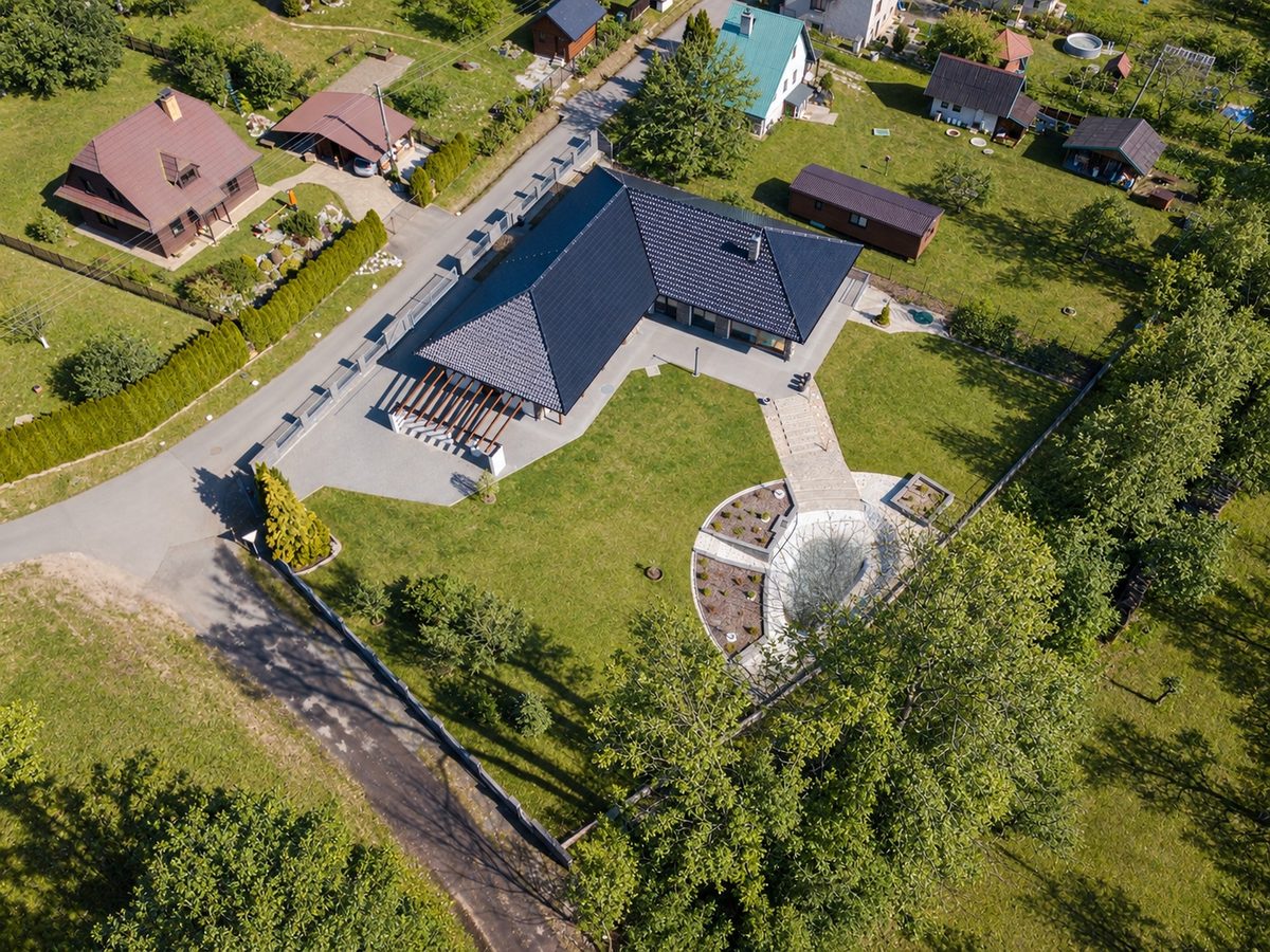 Pozemek z výšky: dům ve tvaru L, ulice podél severní hranice, zahrada s vodním prvkem