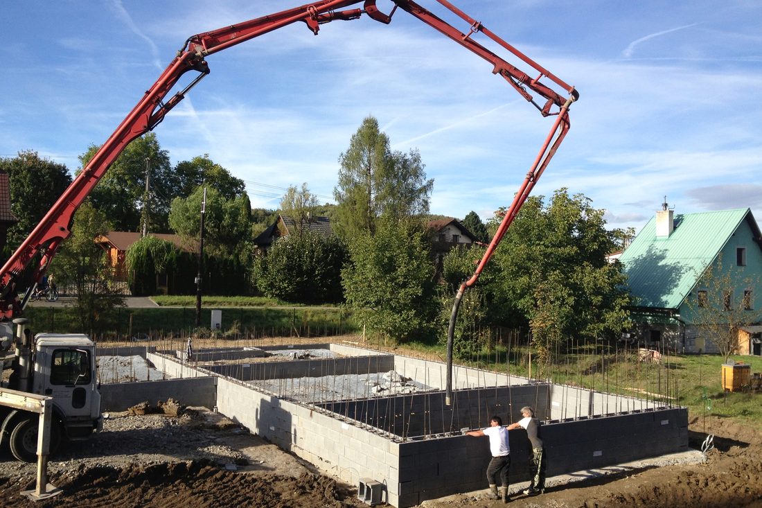 Betonování základů: rameno čerpadla nad stěnami ze ztraceného bednění s ocelovou výztuží